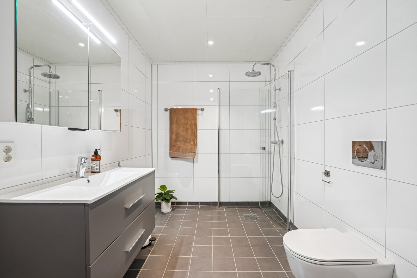 Boligens baderom er romslig, med flislagt gulv som har elektriske varmekabler. På veggene er det baderomsplater og hvite himlingsplater i tak med ledspotter. Galleribilde