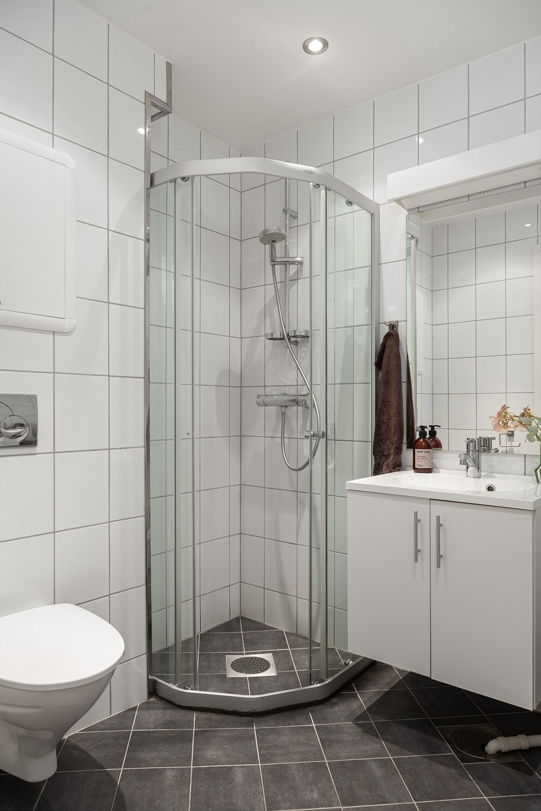 Badet er funksjonelt med nedfelt servant, veggmontert toalett, dusjkabinett og opplegg for vaskemaskin. Gulvet er flislagt og utstyrt med elektriske varmekabler for ekstra komfort. Galleribilde