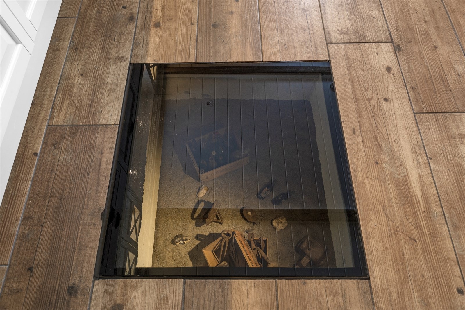 Stilig detalj med glassluke i gulvet mot kjelleren med eget "gårdsmuseum". Galleribilde