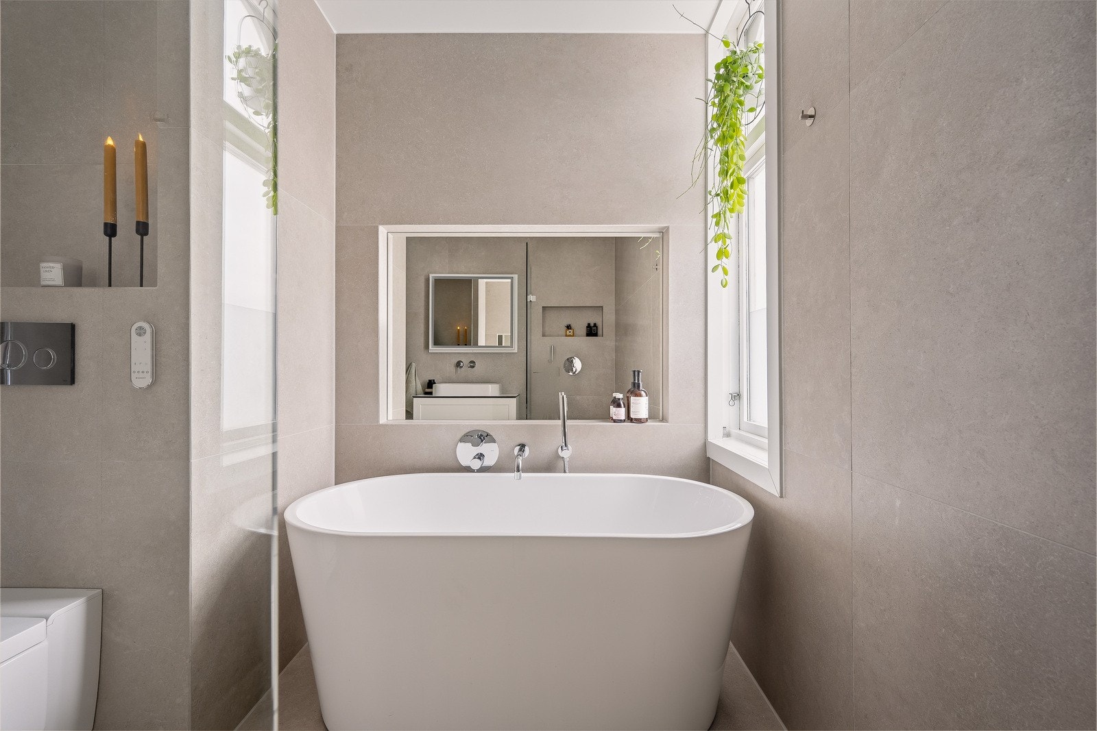 Det frittstående badekaret er plassert under en praktisk nisje med innfelt speil. Galleribilde