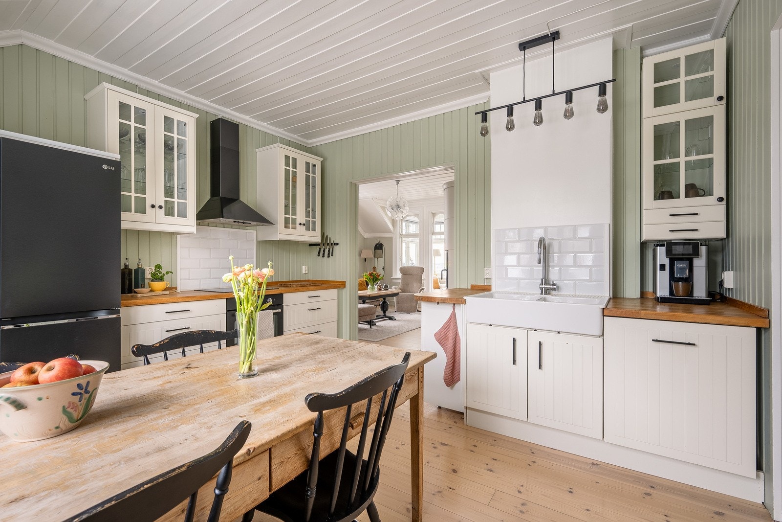 Innredningen kombinerer hvite fronter, overskap med glass og en oppvaskkum i porselen. Galleribilde