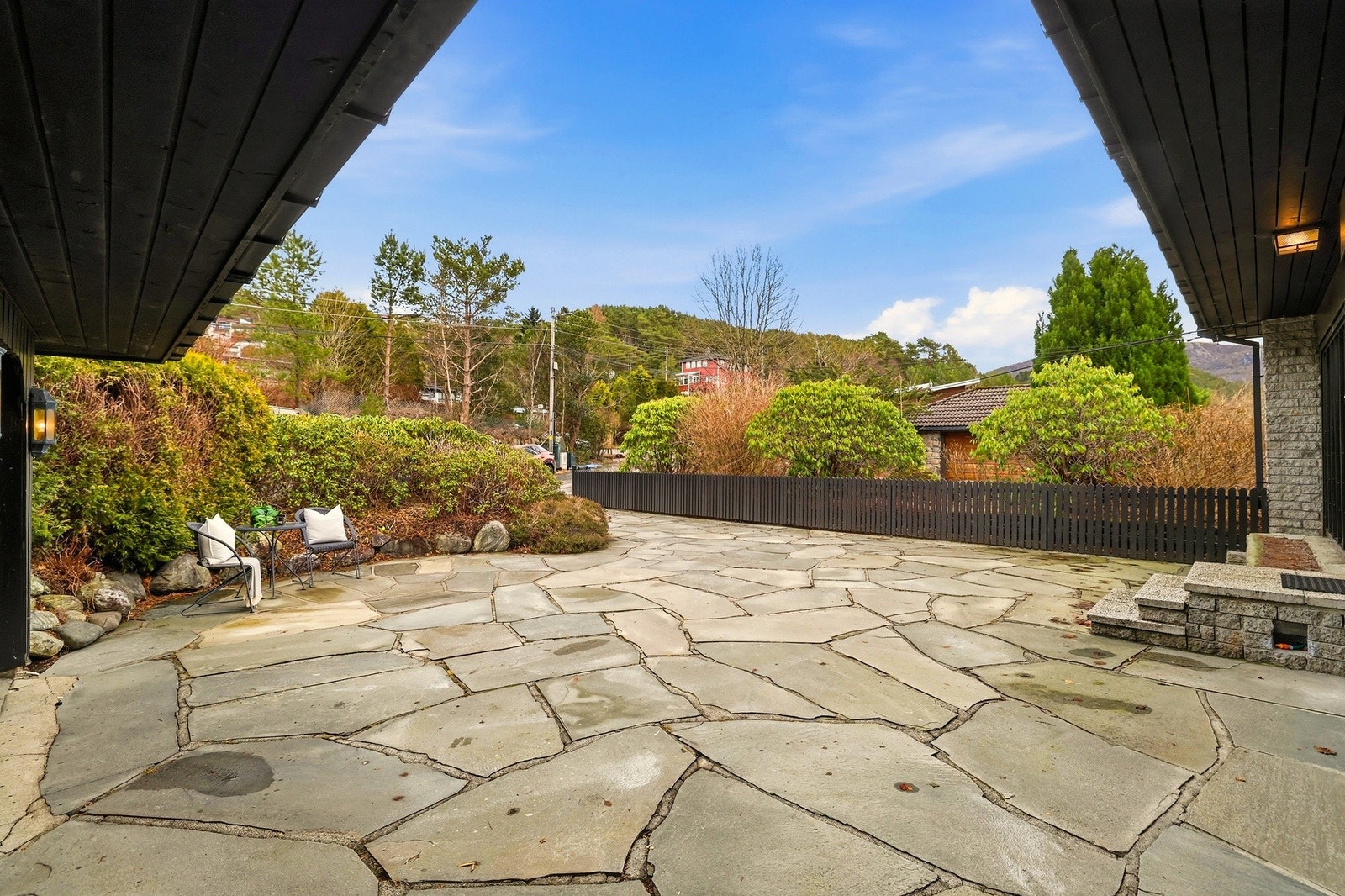 Gjerdet mot naboeiendommen og fin beplantning som skjermer inngangen fra gaten Galleribilde