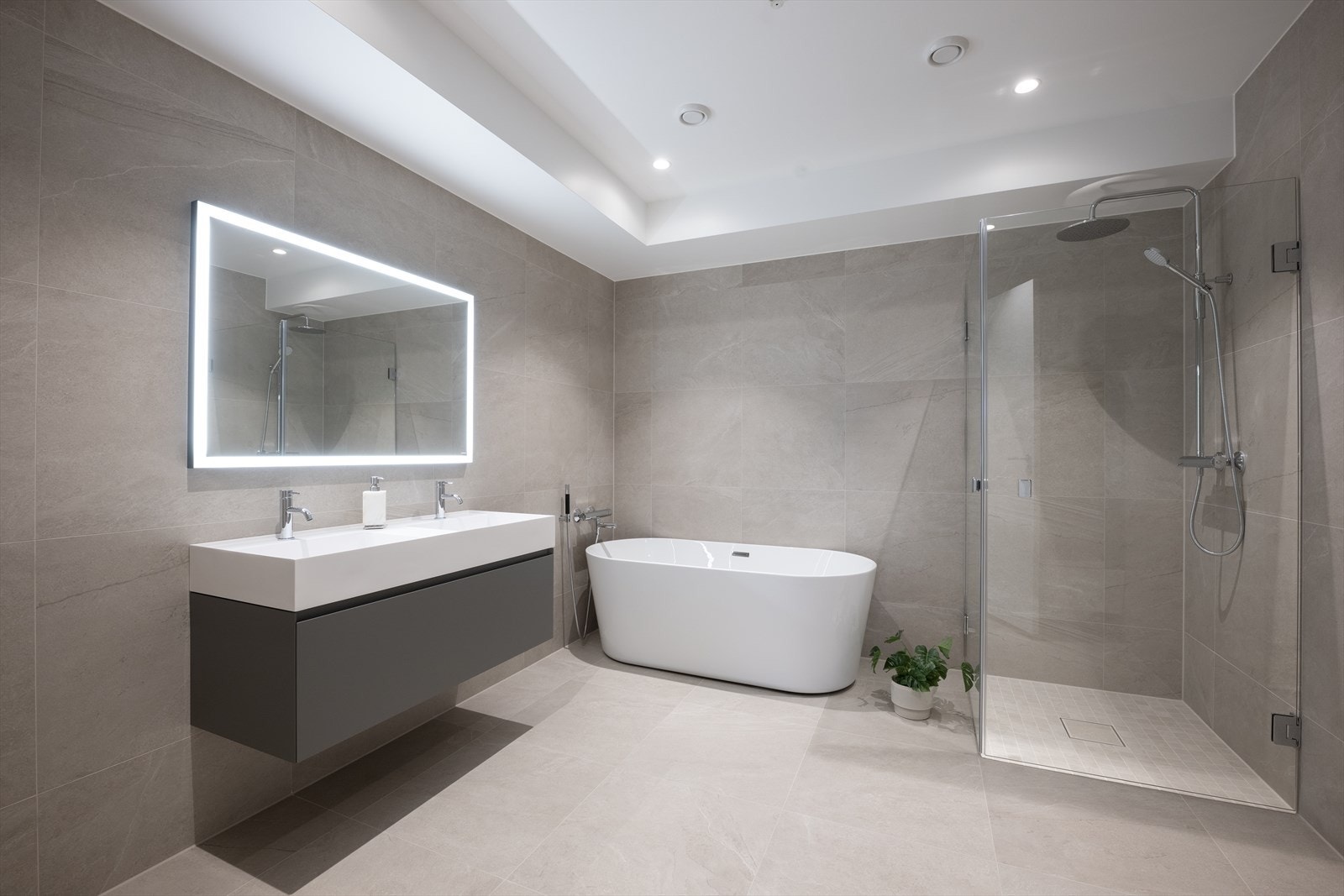 Badene er innredet med store fliser, downlights og speil med integrert belysning Galleribilde