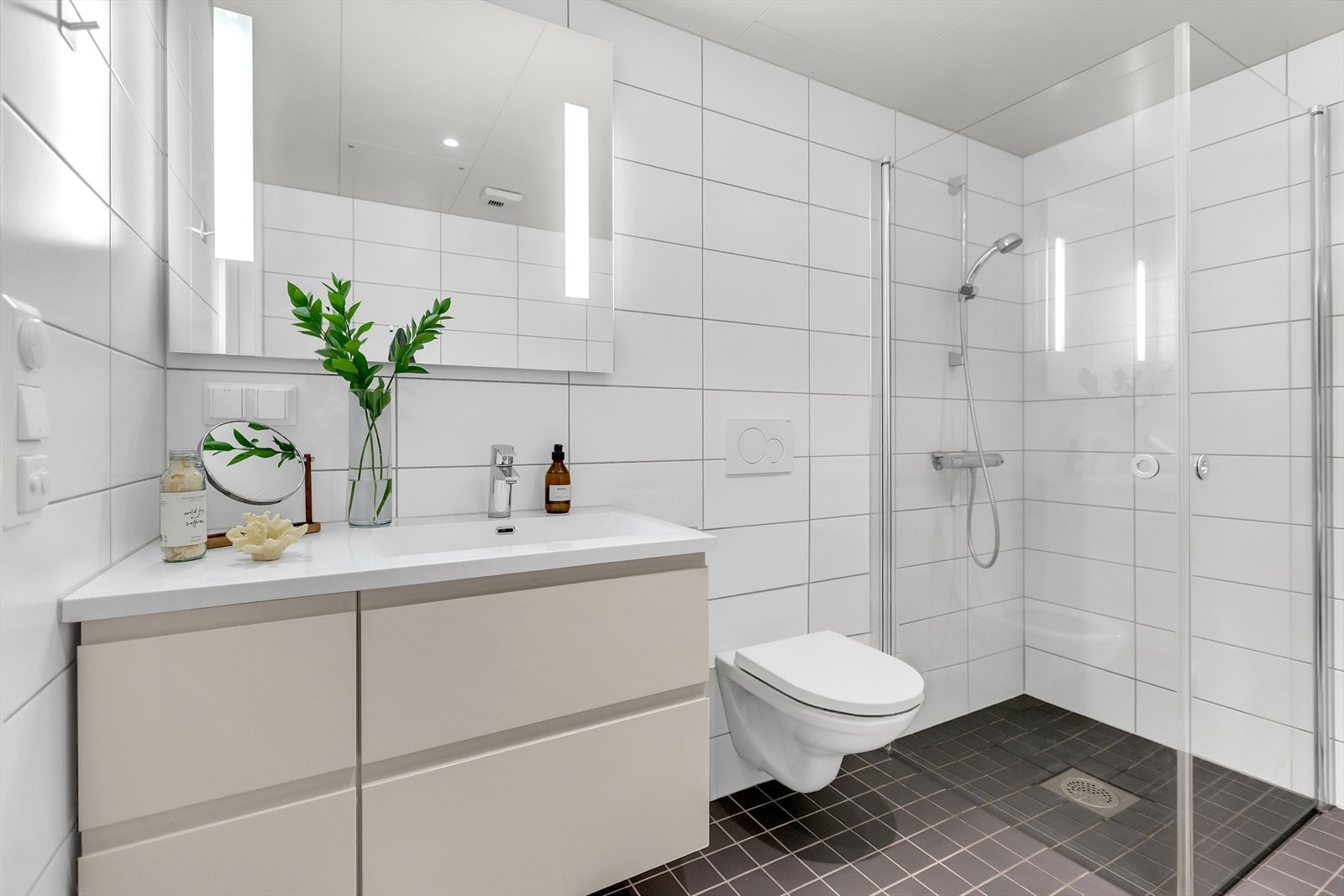 Lekkert bad med flislagte overflater og en praktisk planløsning. Galleribilde