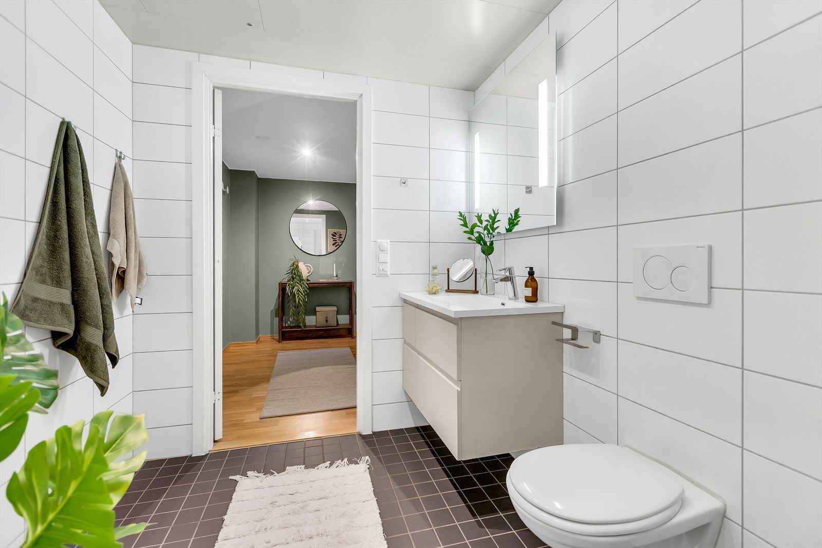 Badet er utstyrt med veggmontert WC, servant med ettgreps blandebatteri i innredning og dusjplass med inn- og utadslående dusjvegger. Galleribilde