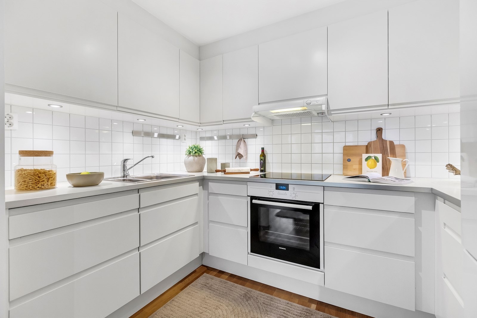 Den lyse utformingen med fliser mellom overskap og laminert benkeplate gir et tidløst uttrykk og er praktisk i bruk. Galleribilde