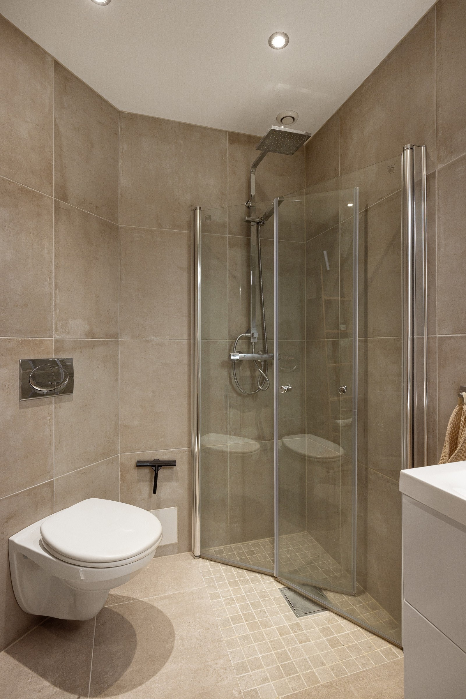 Videre har badet vegghengt servantskap, dusjhjørne med innfellbare glassdører og to-greps armatur påkoblet hånddusj og regndusj, samt vegghengt toalett. Galleribilde