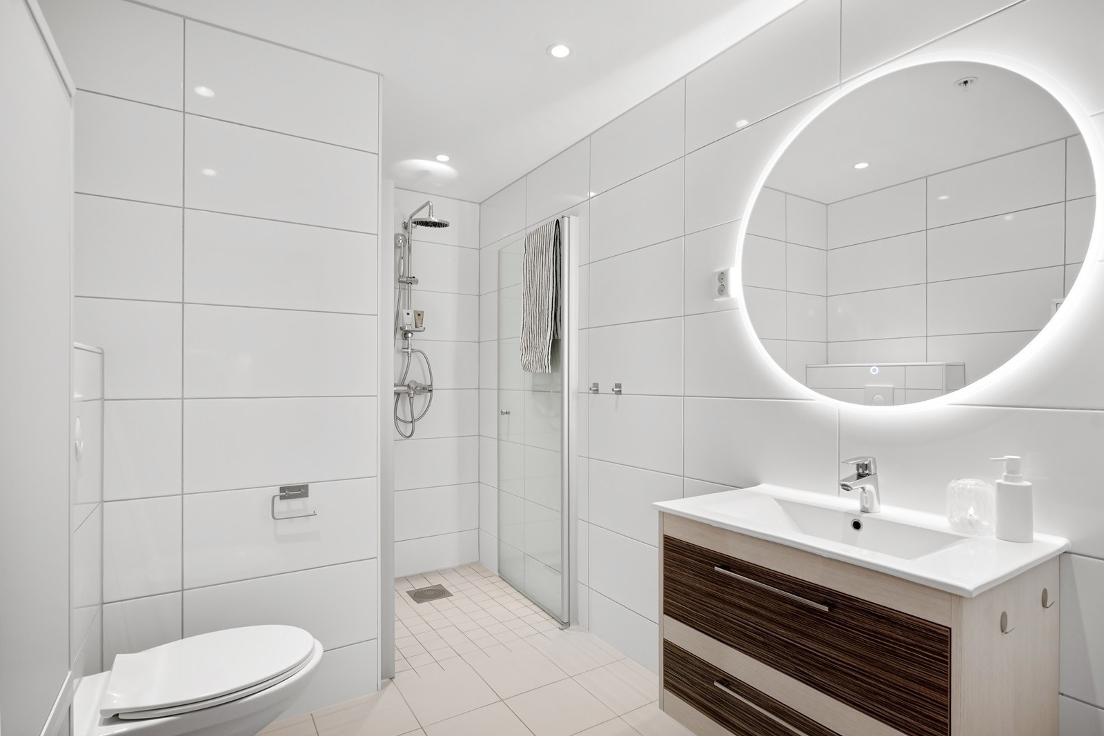 Badet er moderne og romslig, med lyse fliser på vegger og gulv, gulvvarme og dimbare downlights i himlingen. Galleribilde