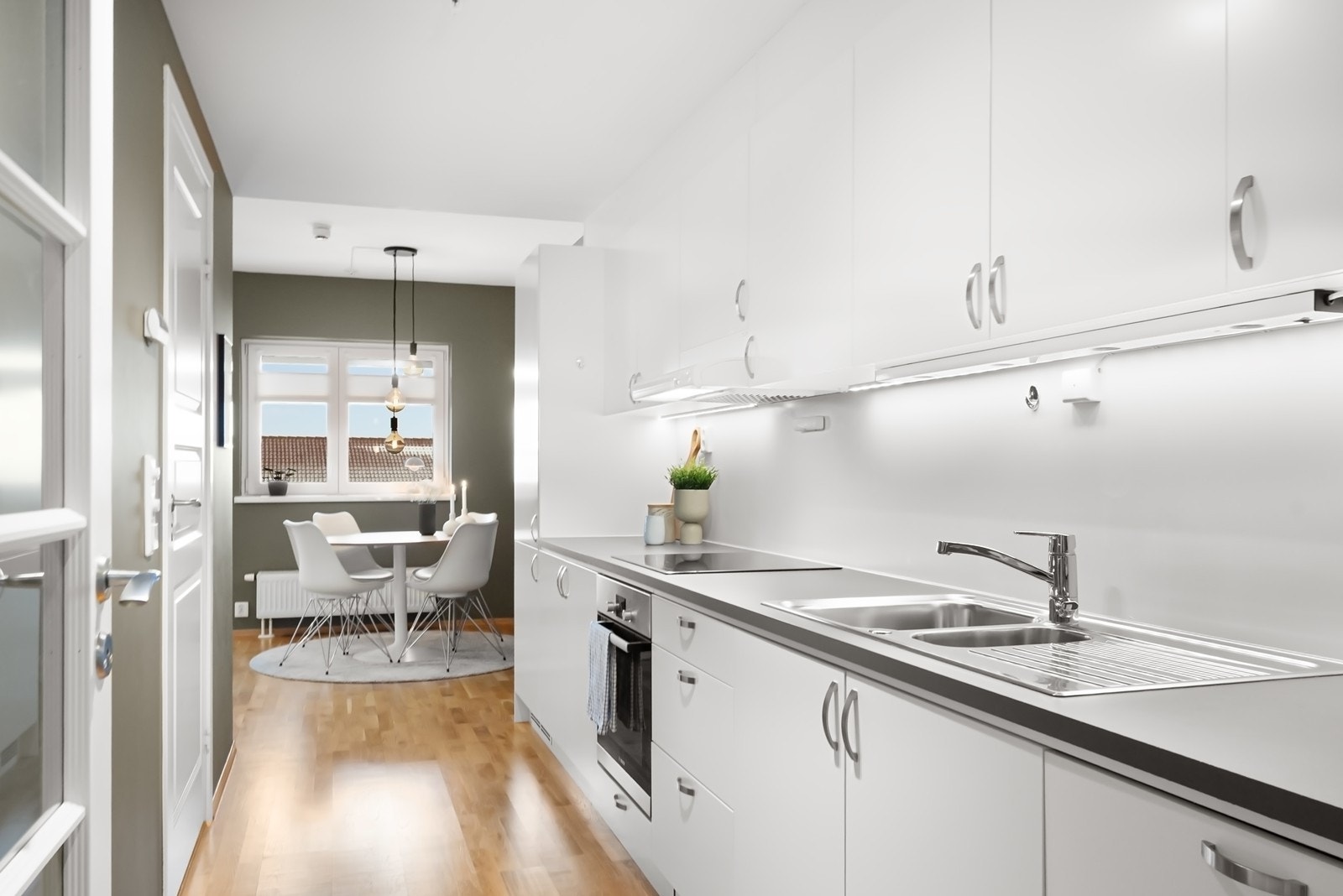 Kjøkkenet har en stilren, én-sidig innredning med slette, hvite fronter og godt med skapplass. Koke- og vaskesone er plassert side om side med praktiske arbeidsflater. Galleribilde