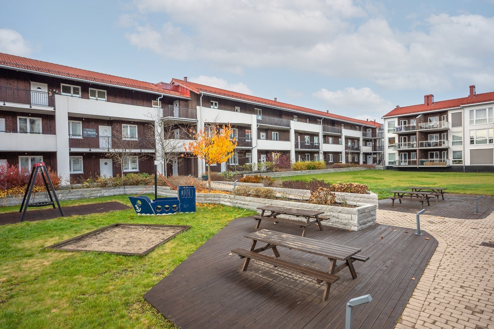 Sameiets fellesareal er pent opparbeidet med gressplen, sittebenker og lekeapparater. Galleribilde