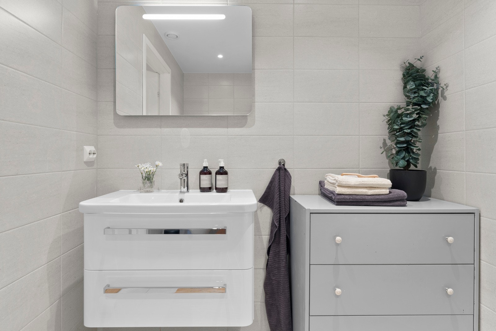 Badet har et stilrent uttrykk med vegg- og gulvfliser i grå toner. Galleribilde