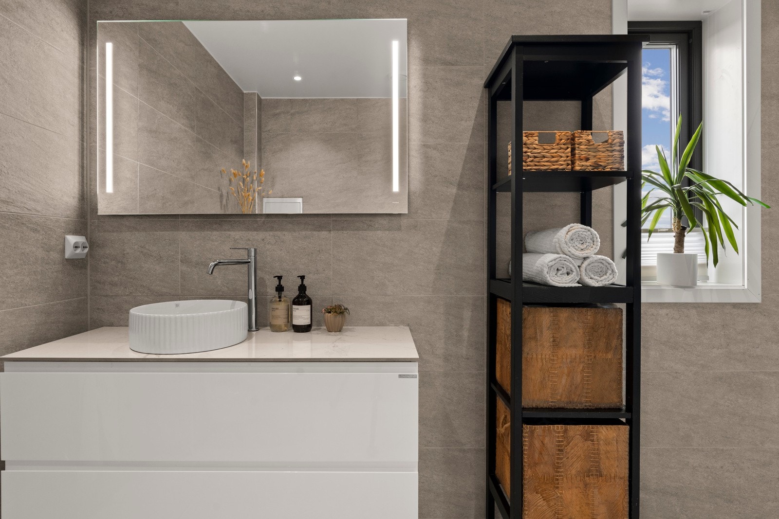 Innredet med servantinnredning, speil med lys på vegg over servant, vegghengt toalett og dusjhjørne med dobbel dusj og svingbare foldedører. Galleribilde