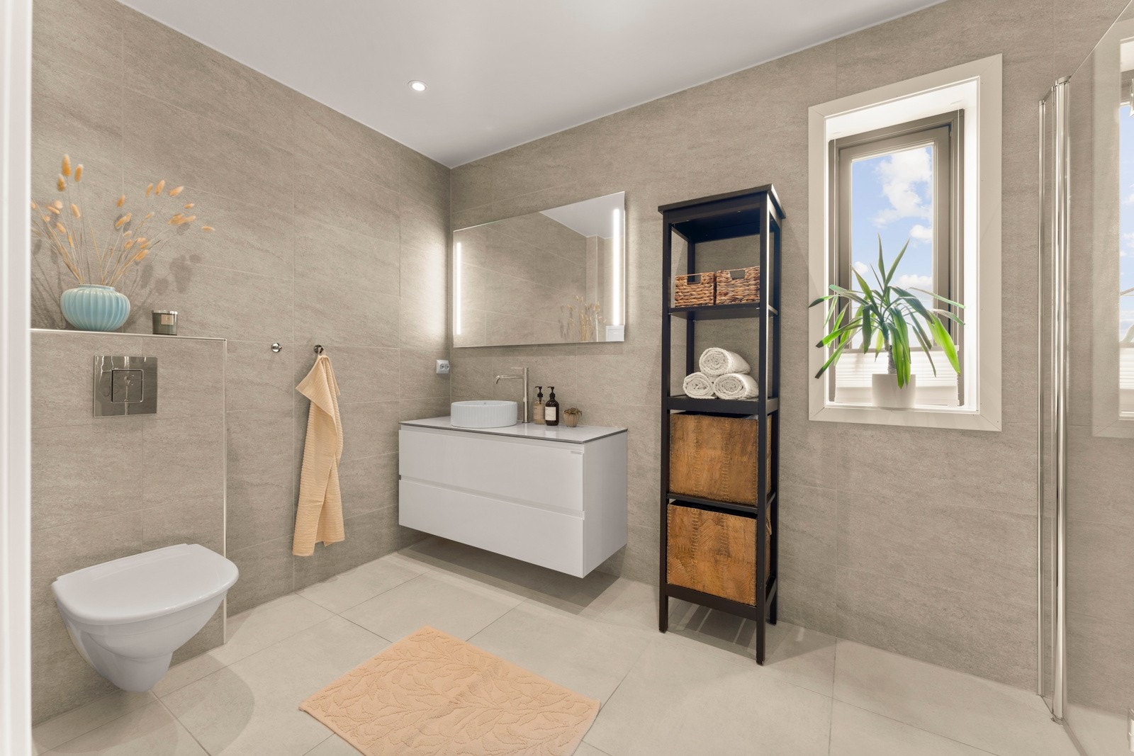 Badet har et stilrent uttrykk med vegg- og gulvfliser i grå toner. Galleribilde