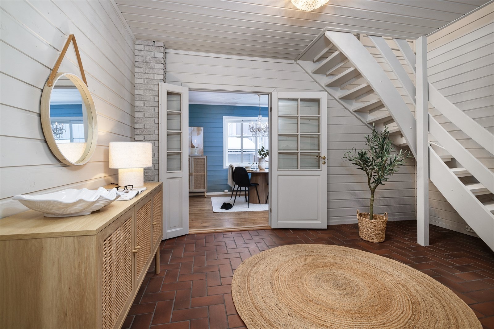 Fra hallen fører doble dører inn til spisestuen, noe som skaper en åpen og inviterende overgang. Galleribilde