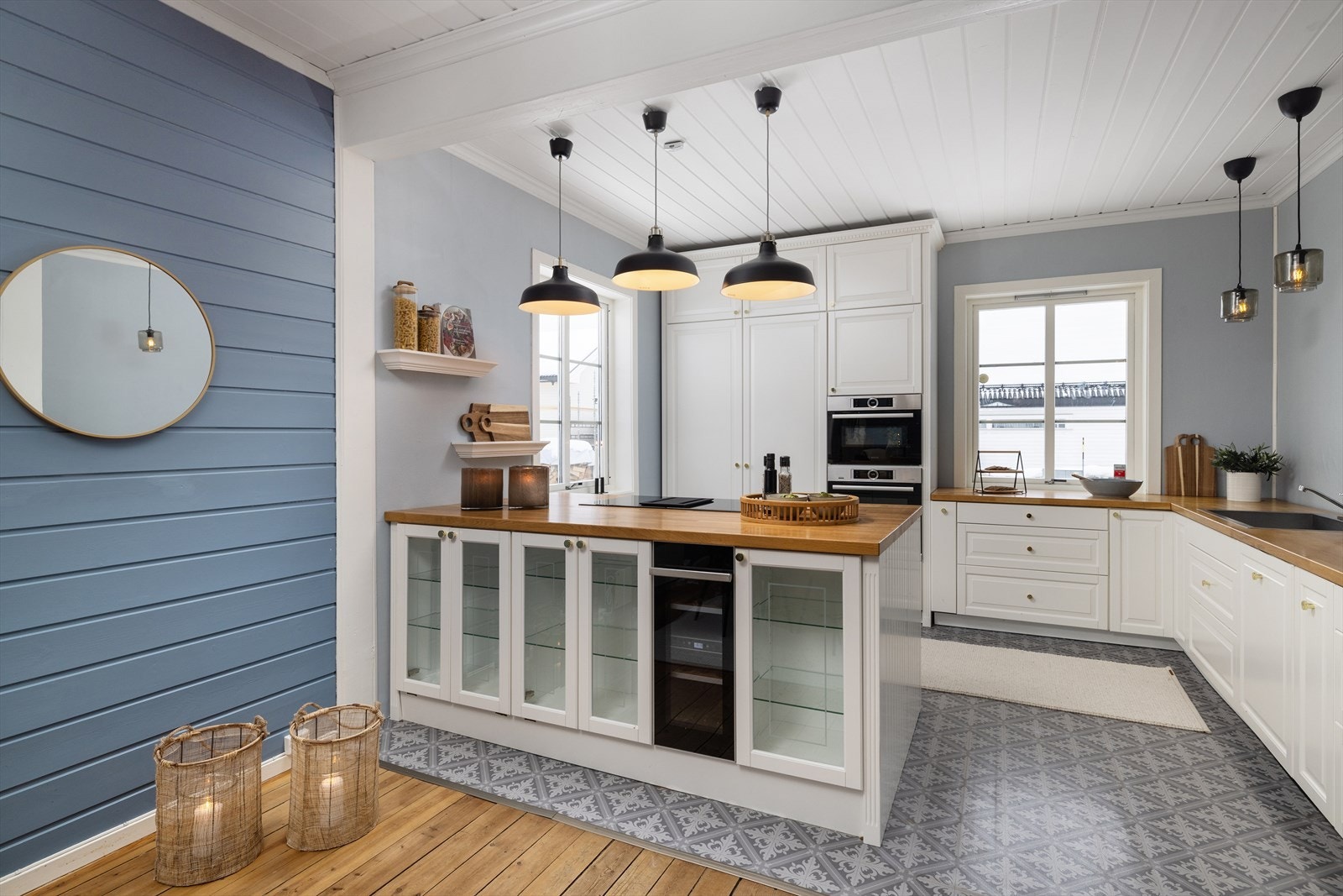 Mot spiseplassen har kjøkkenøya vitrineskap med belysning og et praktisk, integrert vinskap. Galleribilde