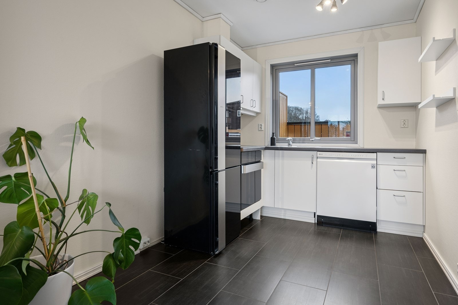 Hvit, glatt kjøkkeninnredning i åpenløsning med stuen. Galleribilde