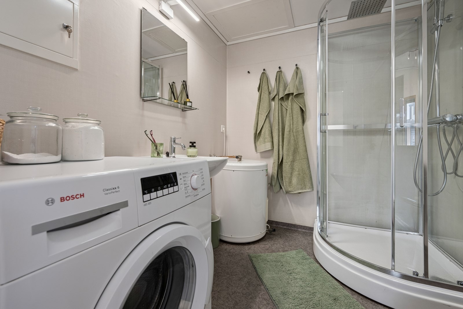 Badet er innredet med dusjkabinett, toalett, servant og opplegg for vaskemaskin. Galleribilde