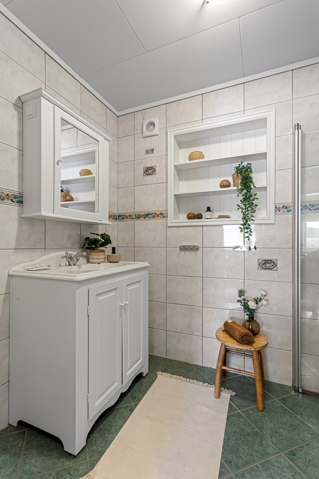 Speilskap på vegg over servant. Plassbygd hylle i vegg. Dusjhjørne med dører og gulvstående toalett. Galleribilde