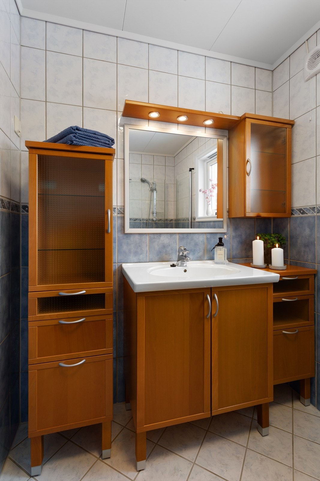 Speil og lys på vegg over servant. Dusjhjørne med glassdører og gulvstående toalett. Galleribilde