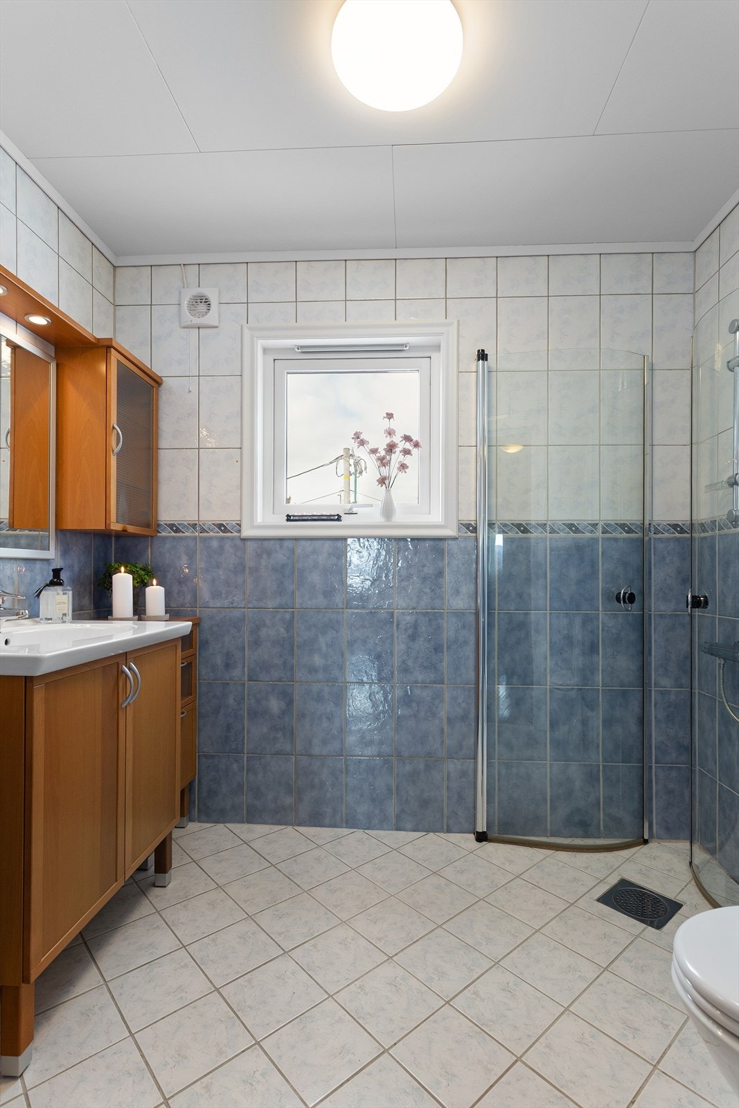 Flislagt bad i hybelen med gulvvarme. Innredning med glatte fronter og vitrineskap. Galleribilde