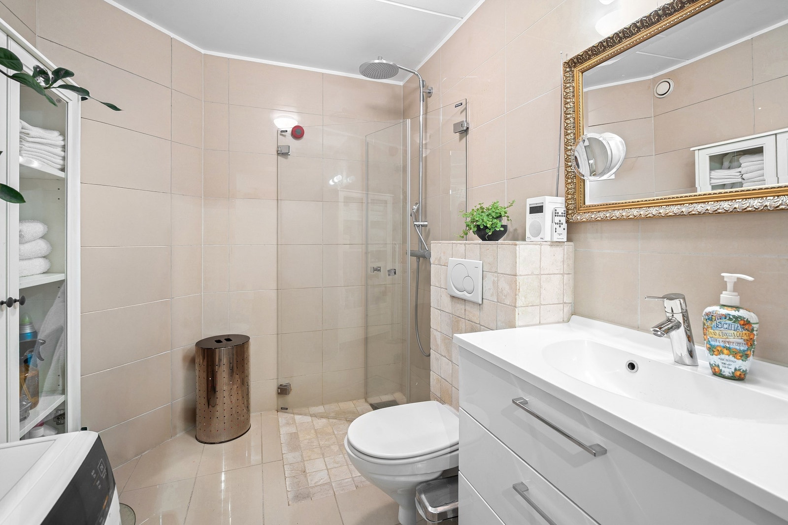 Flislagt bad med varmekabler i gulv. Rommet er utstyrt med vegghengt toalett tilkoblet innebygget sisterne og vegghengt servantskap med ovenpåliggende vask. Videre er det nedsenket dusjsone med innfellbare dusjdører og armatur tilkoblet hånd- og regndusj. Galleribilde