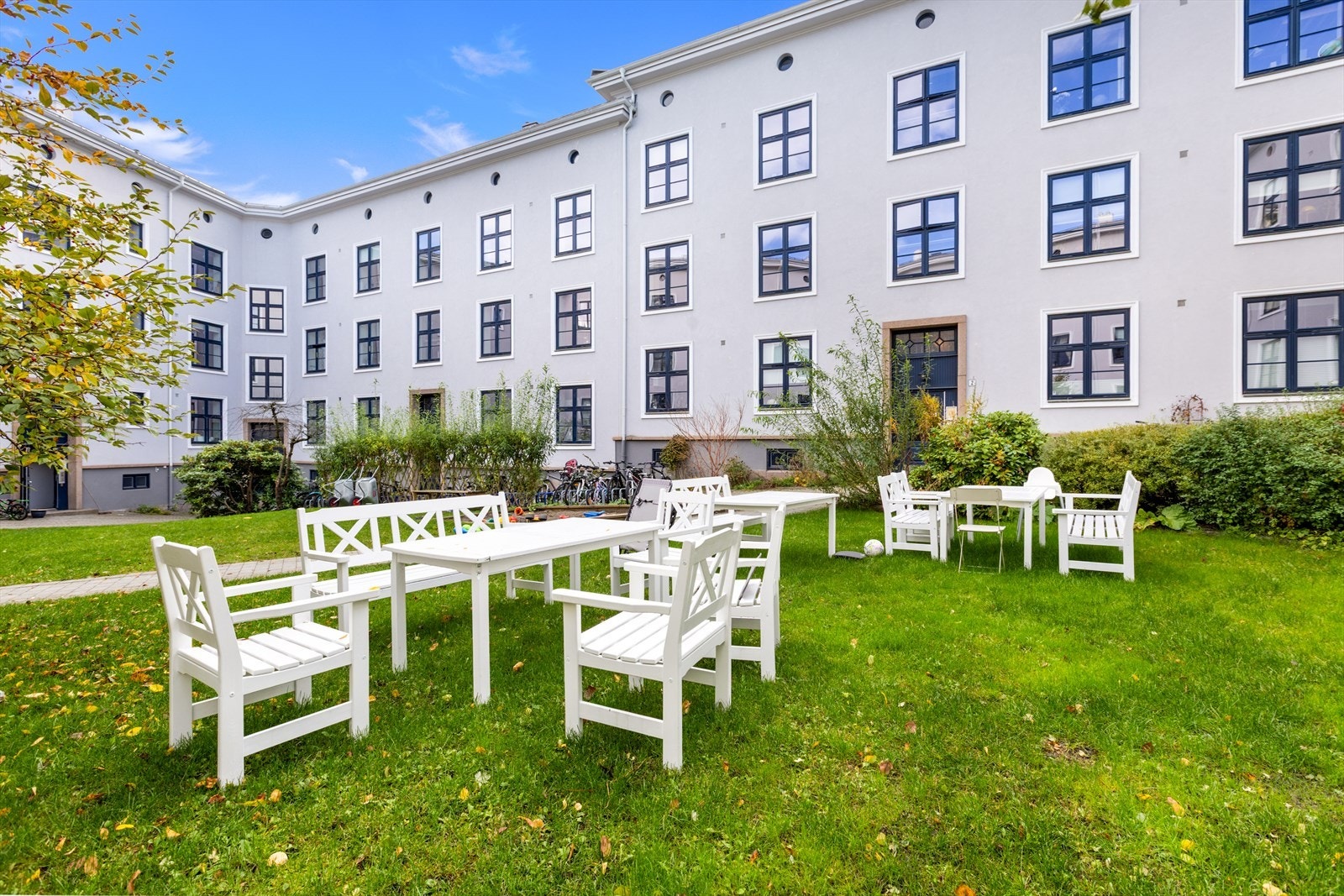 Hyggelig og frodig bakgård med sitteplasser og sykkelparkering. Galleribilde