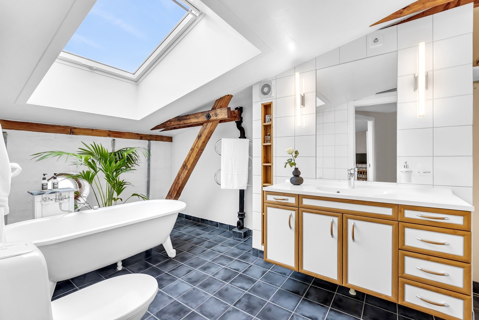 Romslig bad som har en særpreget og lun atmosfære med synlige trebjelker og takvindu som gir godt naturlig lys. Galleribilde