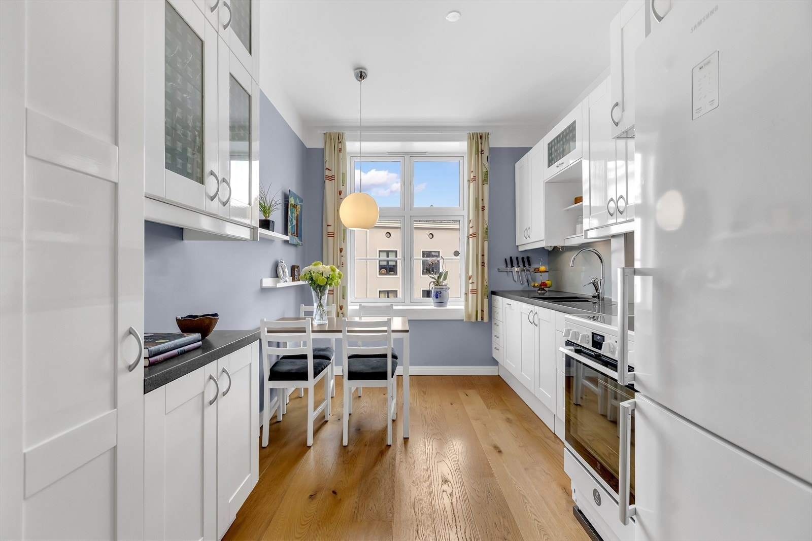 Kjøkkenet fremstår lyst og tidløst med hvite, laminerte kjøkkenskrog og gode skap- og benkeplateløsninger. Galleribilde