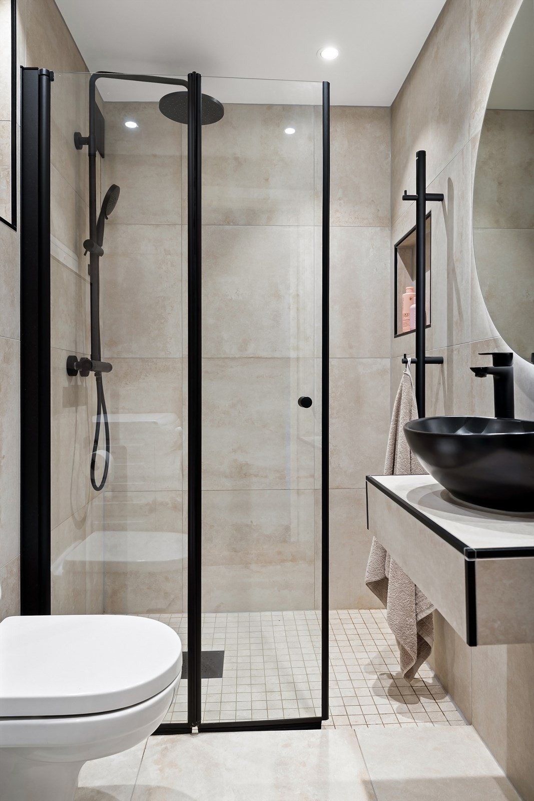 Videre er badet utstyrt med vegghengt toalett, ovenpåliggende servant, speil med integrert belysning over og opplegg for vaskemaskin Galleribilde