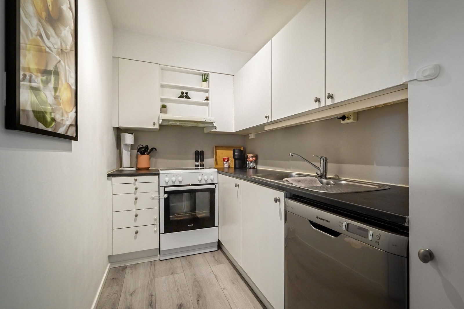 Funksjonelt kjøkken med hvite fronter, benkeplate av laminat og nedfelt oppvaskkum med ett-greps armatur Galleribilde