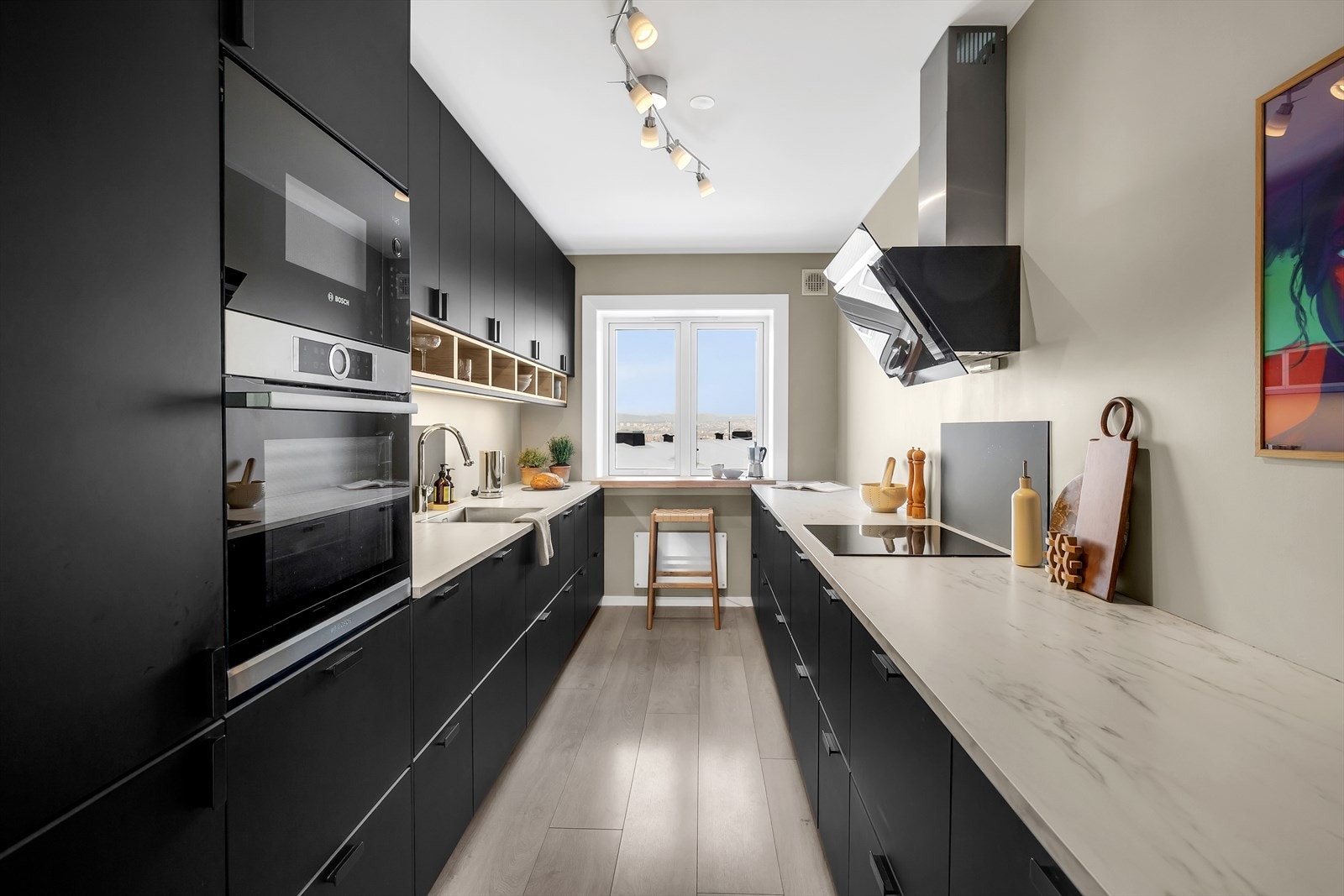 Moderne kjøkken med slette fronter og rikelig med oppbevaringsplass i skap og skuffer. Laminert benkeplate og belysning under overskap. Galleribilde