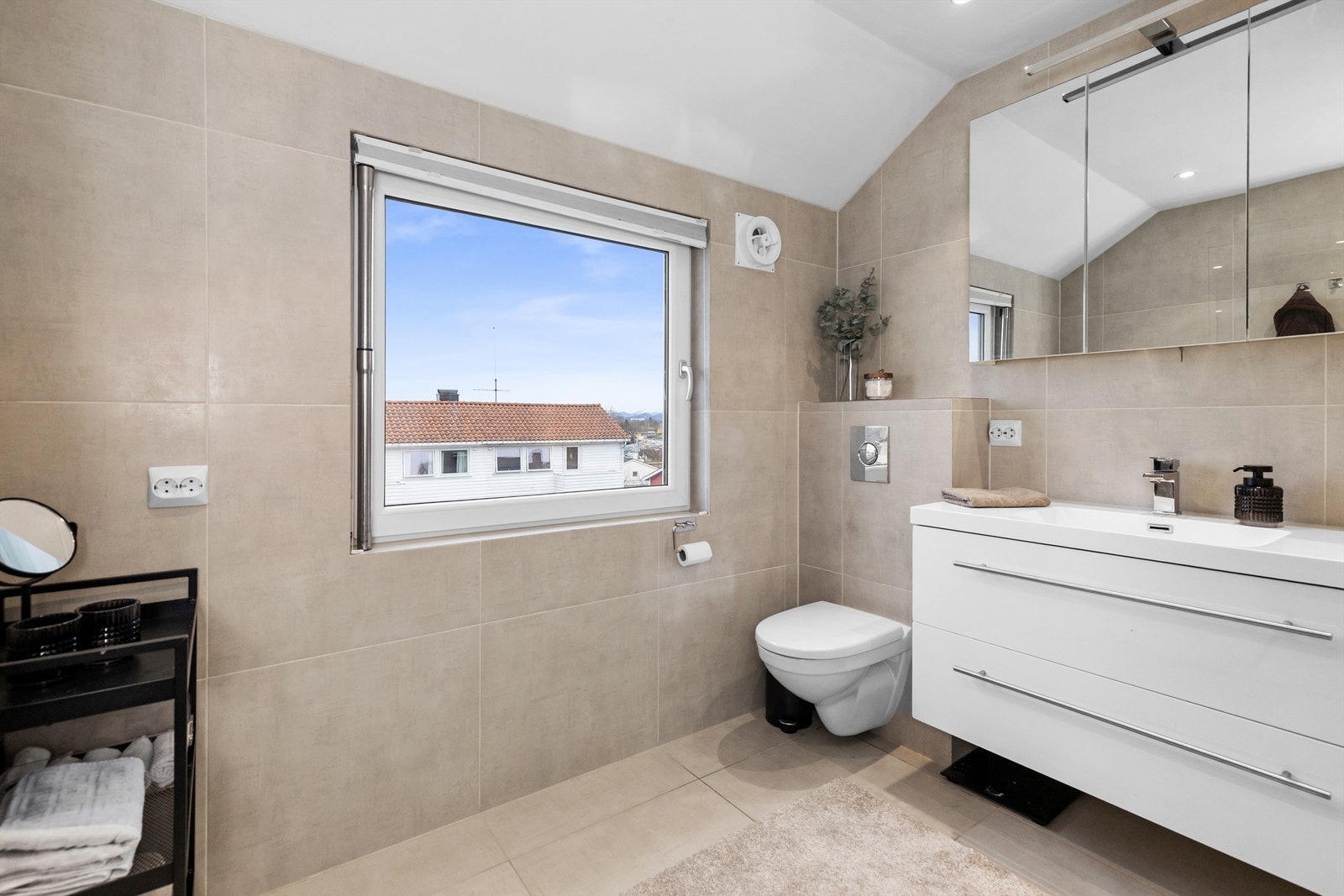 Badet er utstyrt med vegghengt toalett, servantinnredning og dusjhjørne. Galleribilde