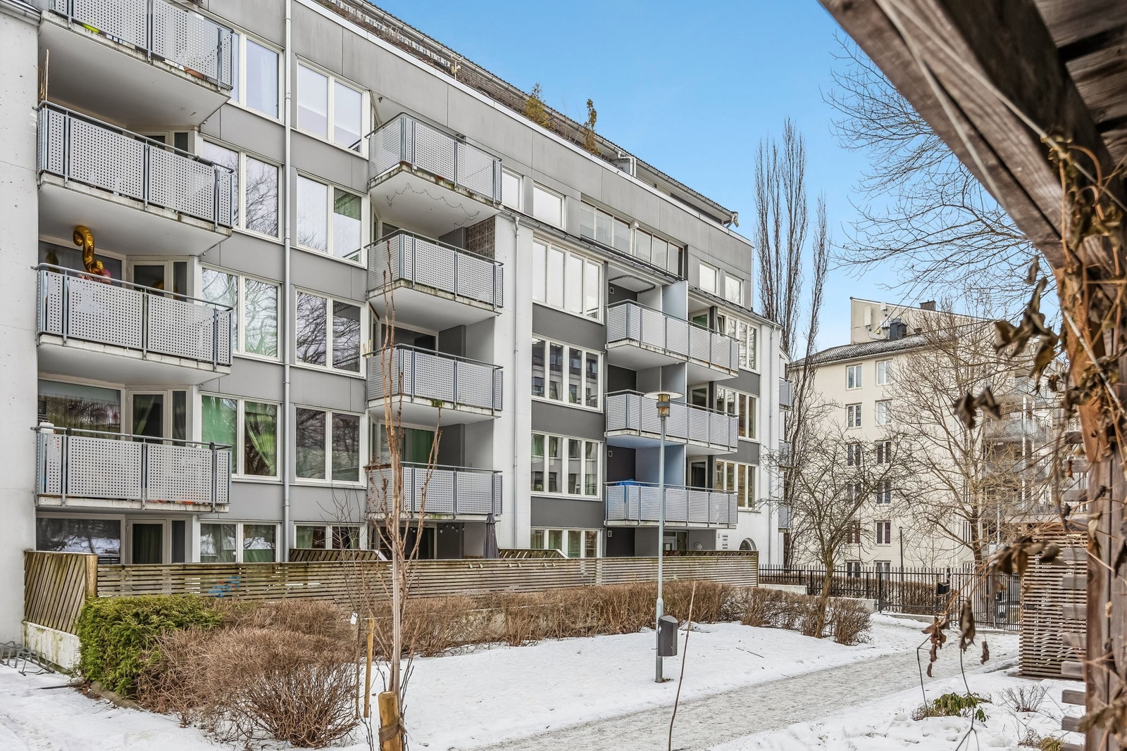 Fasade og privat inngjerdet bakgård for sameiet. Frodig og grønt om sommeren. Galleribilde