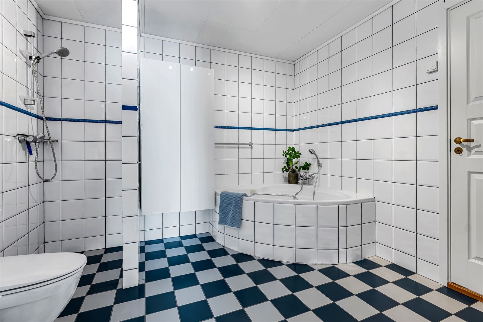 Badet er innredet med servantinnredning med ettgreps blandebatteri, speil, gulvstående toalett, badekar med spylefunksjon og åpen dusjnisje. Galleribilde