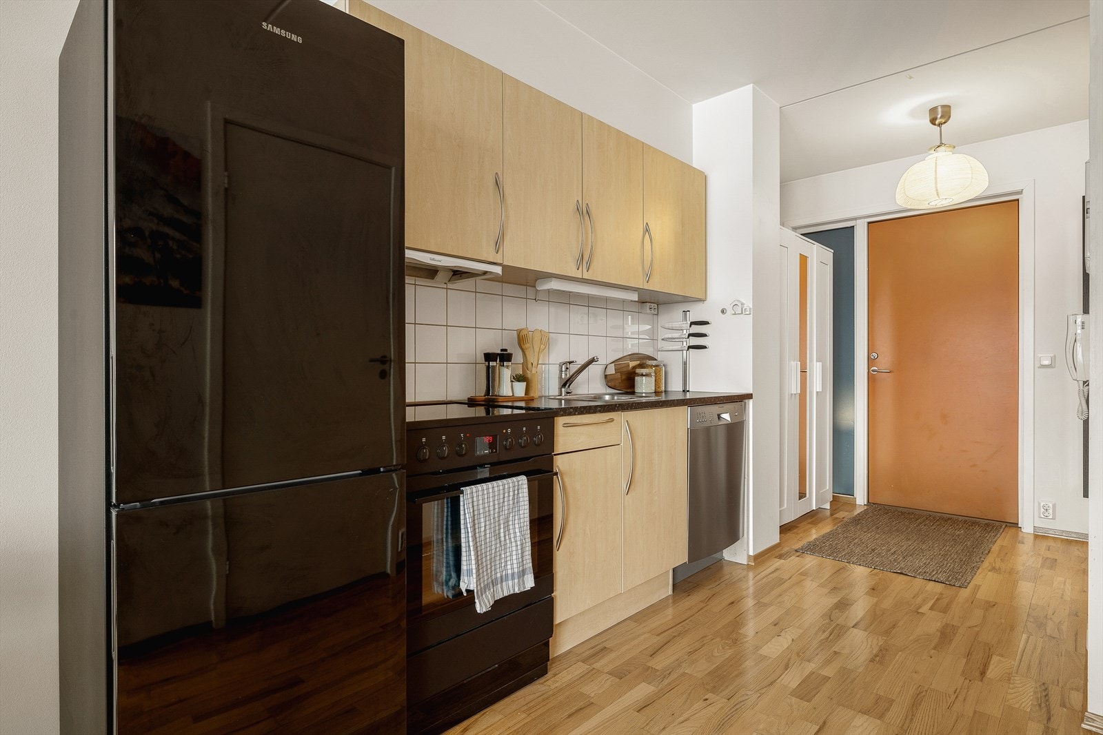 Tidløst kjøkken med trefargede, slette fronter og en praktisk laminatbenkeplate. Galleribilde