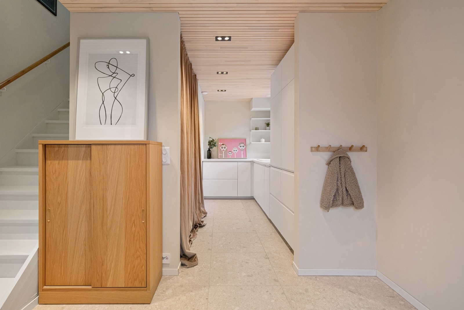 Entréen er praktisk tilknyttet en vaskeromsnisje med garderobeskap, benk med skap og skuffer, vask og opplegg for vaskemaskin. Galleribilde