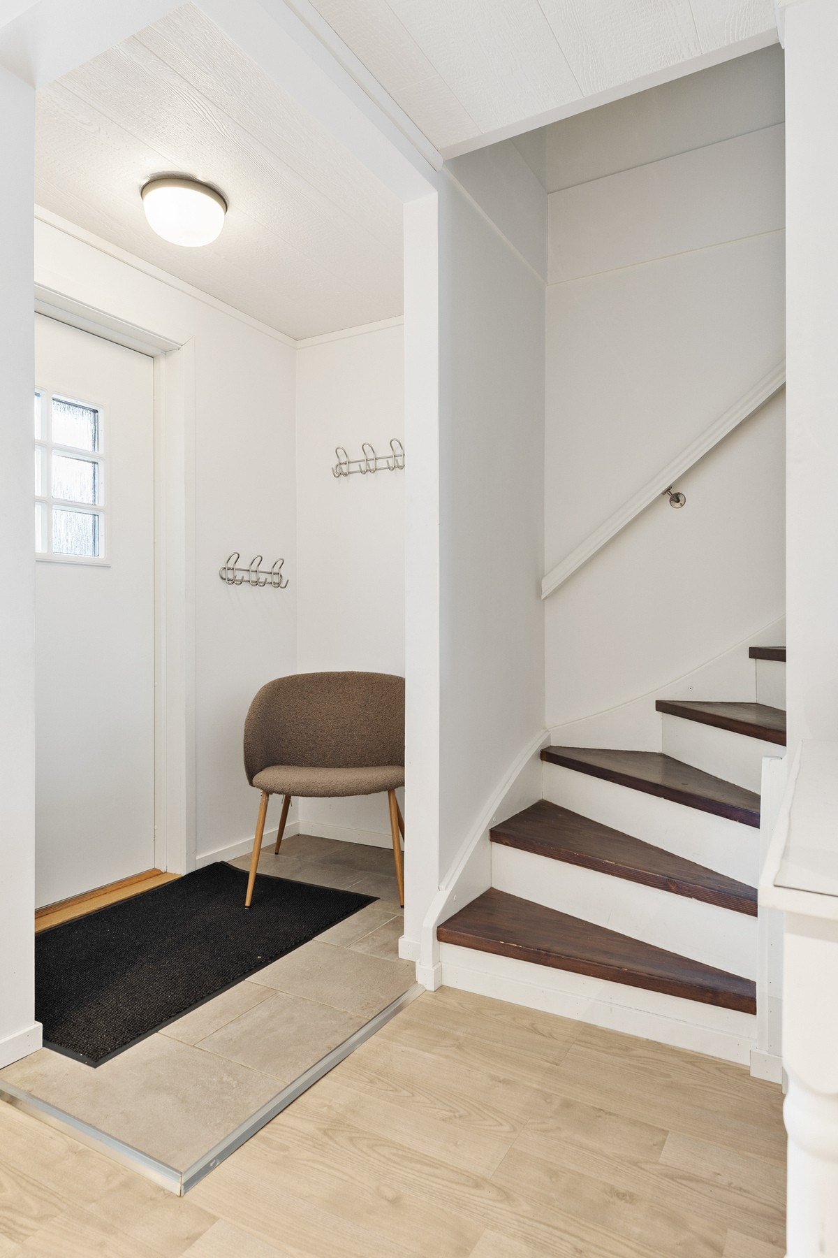 Fra entréen leder en tretrapp med sving og lukkede trinn opp til 2. etasje Galleribilde