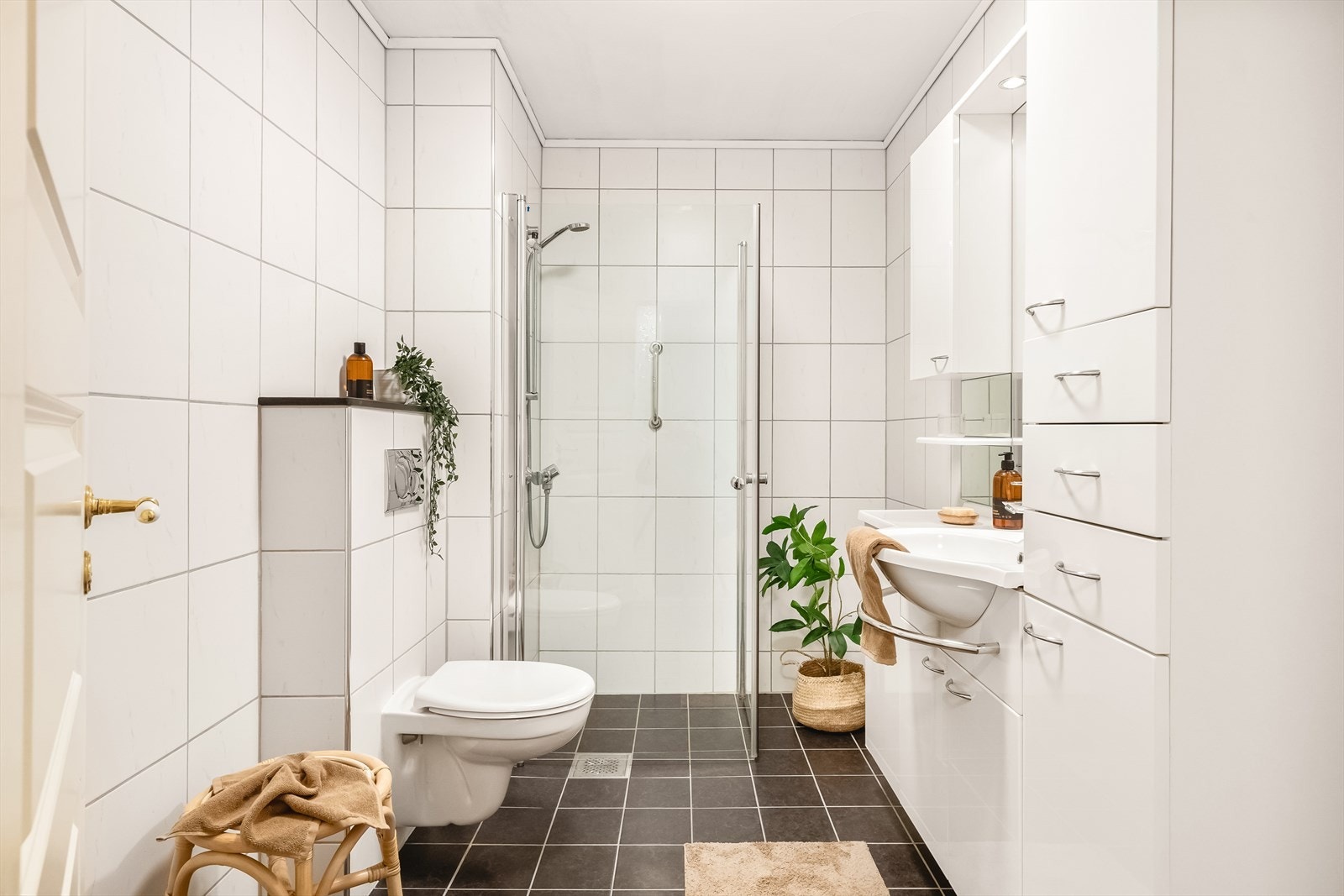 Baderommet har vegghengt toalett, innfellbare dusjvegger i glass og heldekkende servant med masse oppbevaring. Det er opplegg for både vaskemaskin og tørketrommel på badet. Galleribilde