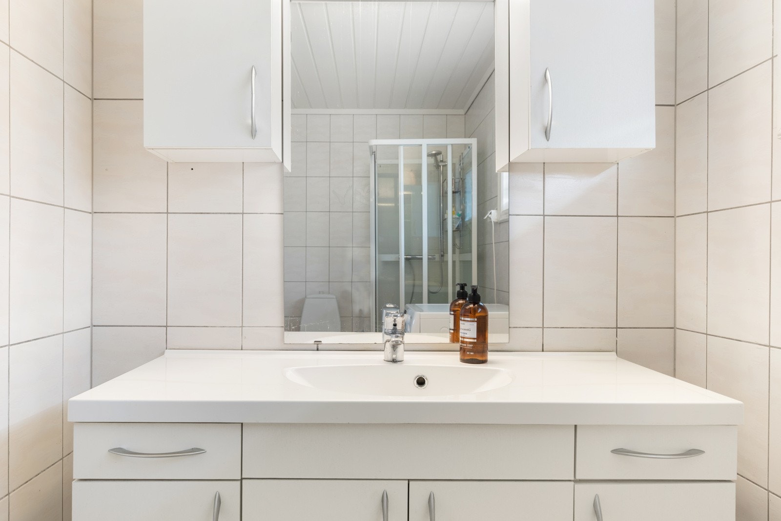 Badet er innredet med godeskapløsninger, servant med underskap, klosett og et dusjkabinett Galleribilde