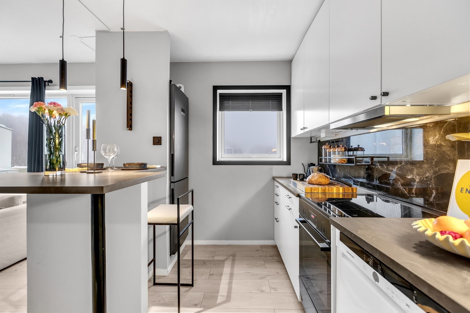 Fliser mellom benk og overskap gir et praktisk og helhetlig uttrykk, og det er belysning under overskapene som gir gode arbeidsforhold. Galleribilde