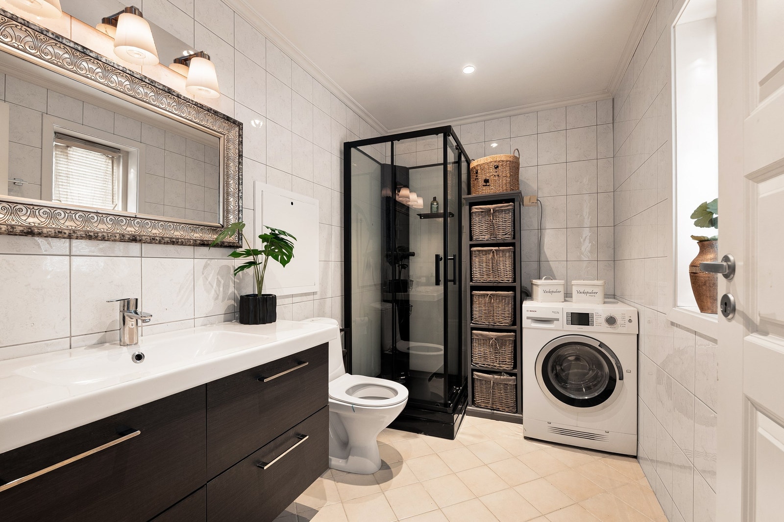 Flislagt bad med dusjkabinett og praktisk opplegg for vaskemaskin. God oppbevaringsplass og en funksjonell planløsning. Galleribilde