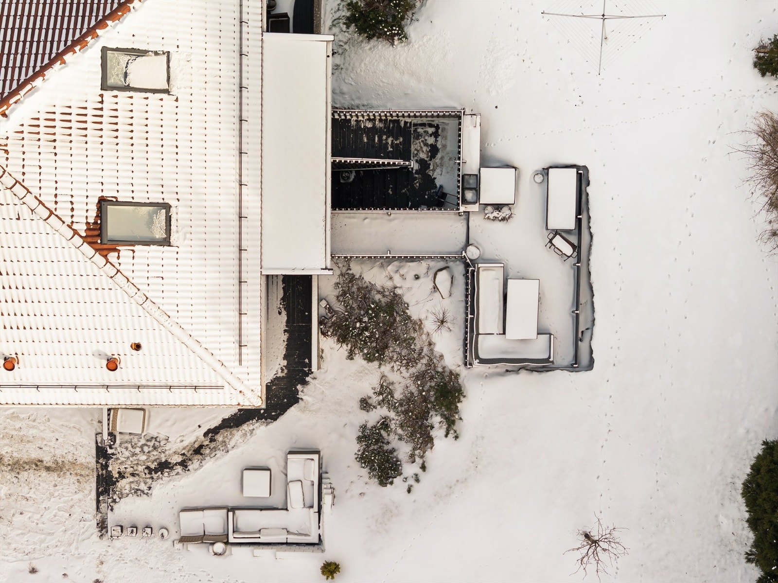 Dronefoto av eiendommens bakgård som viser romslig uteområde med flere soner for sittegrupper. Galleribilde