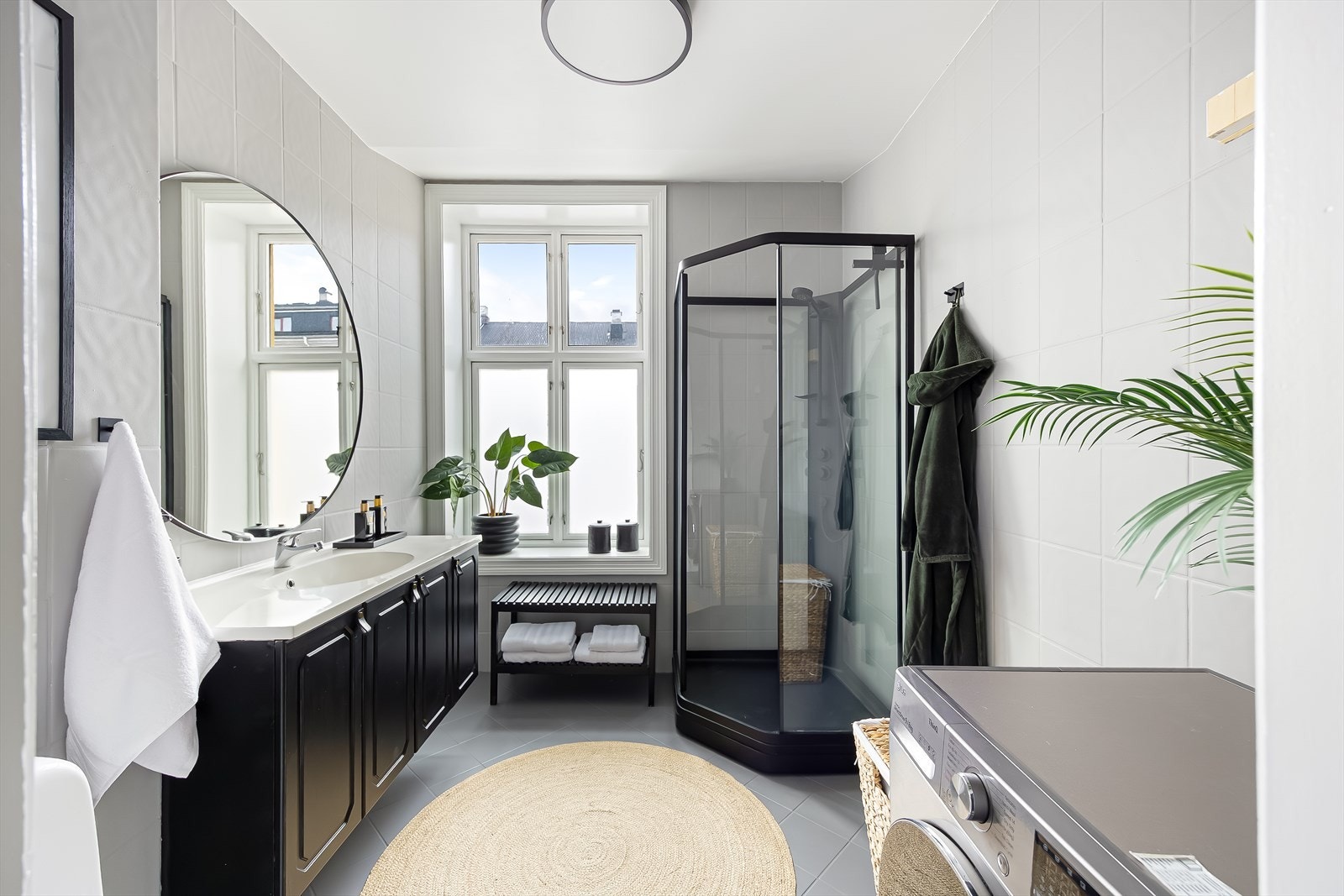 Flislagt bad med dusjkabinett og vindu mot bakgård med naturlig lysinnslipp. Galleribilde