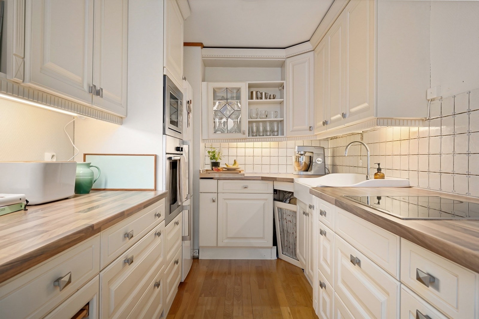 Hvit innredning med profilerte fronter, laminat benkeplate, nedfelt oppvaskkum i porselen og ett-greps armatur Galleribilde