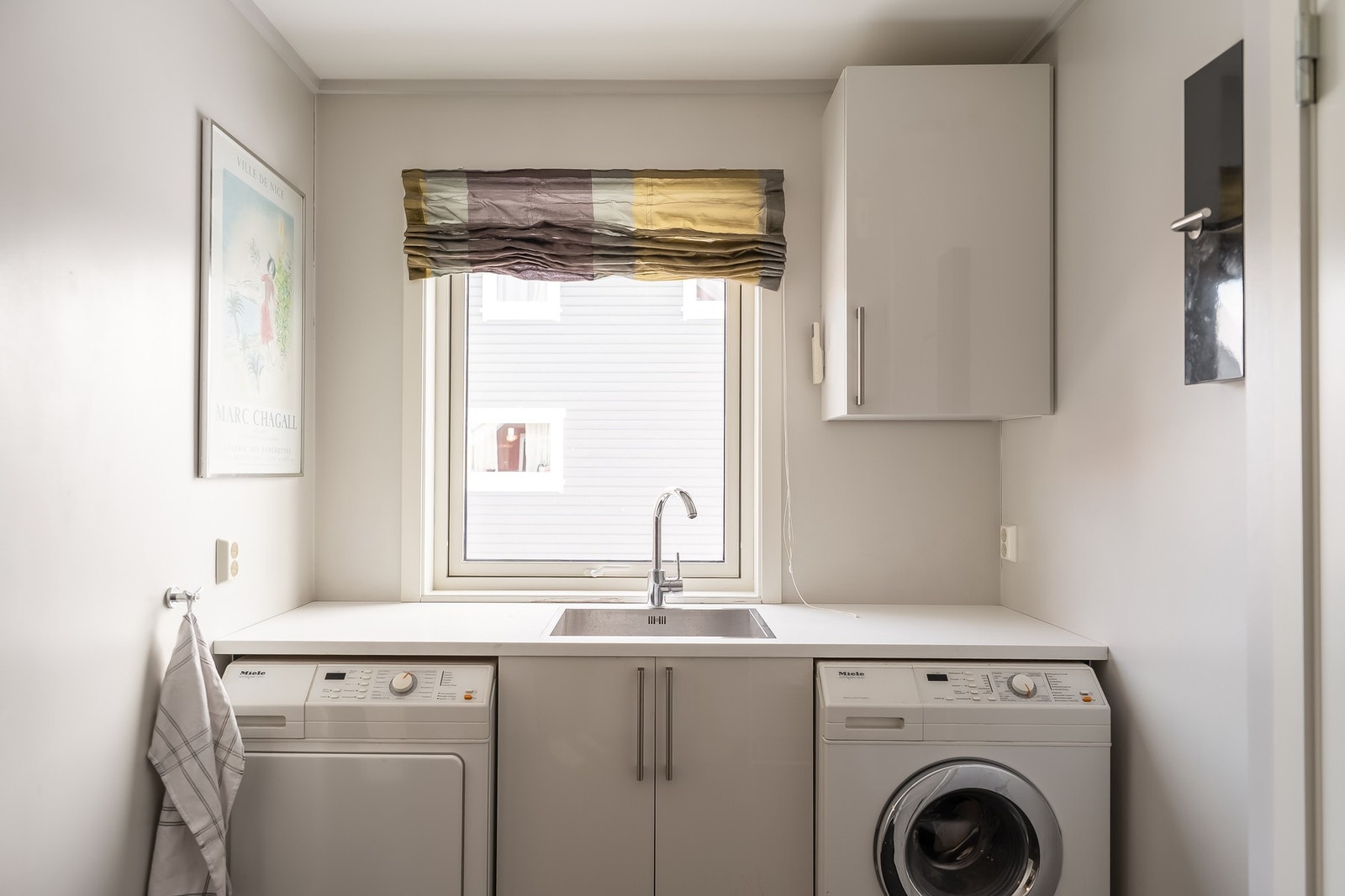 Et praktisk vaskerom med benkeplass og opplegg for vaskemaskin Galleribilde