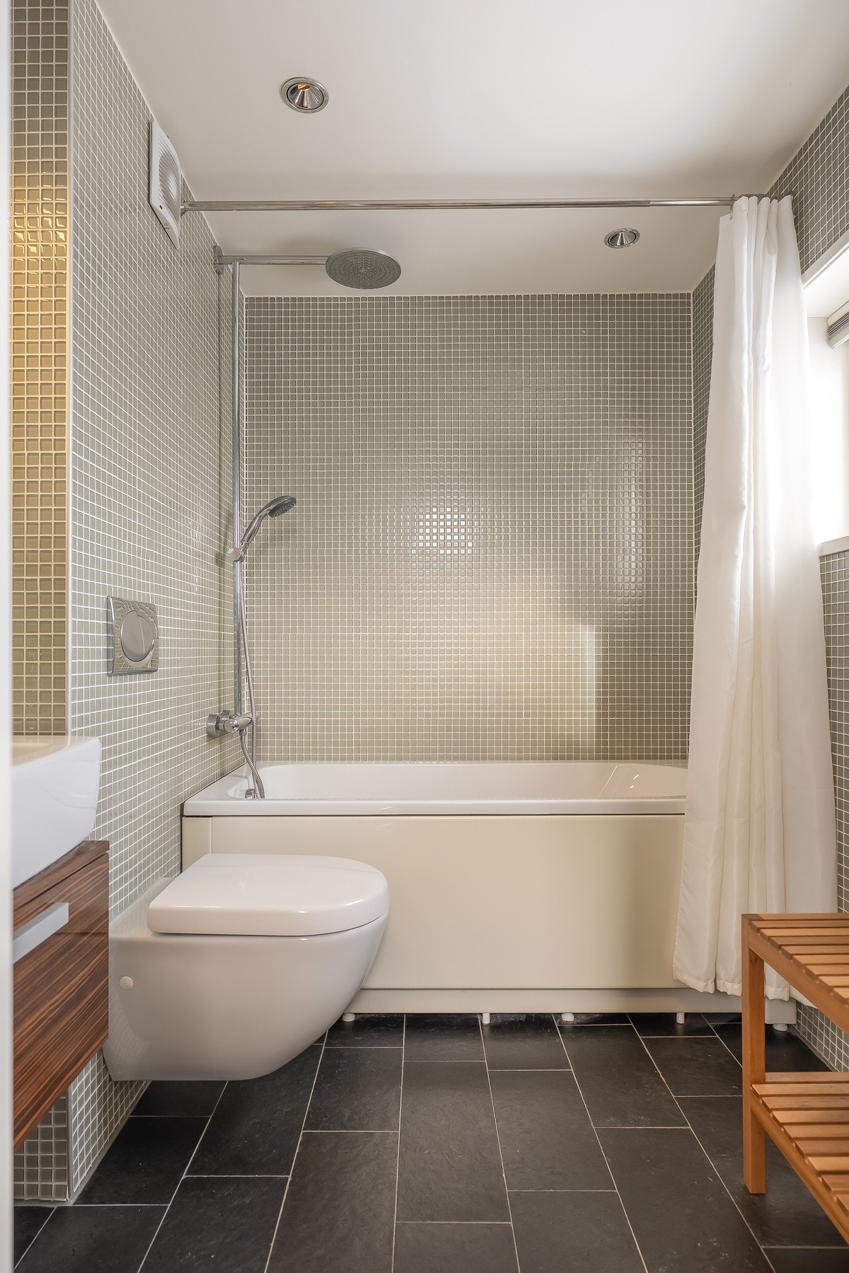 Flislagt og delikat bad fra 2007. Vegghengt wc, badekar med dusj og servantskap. Galleribilde