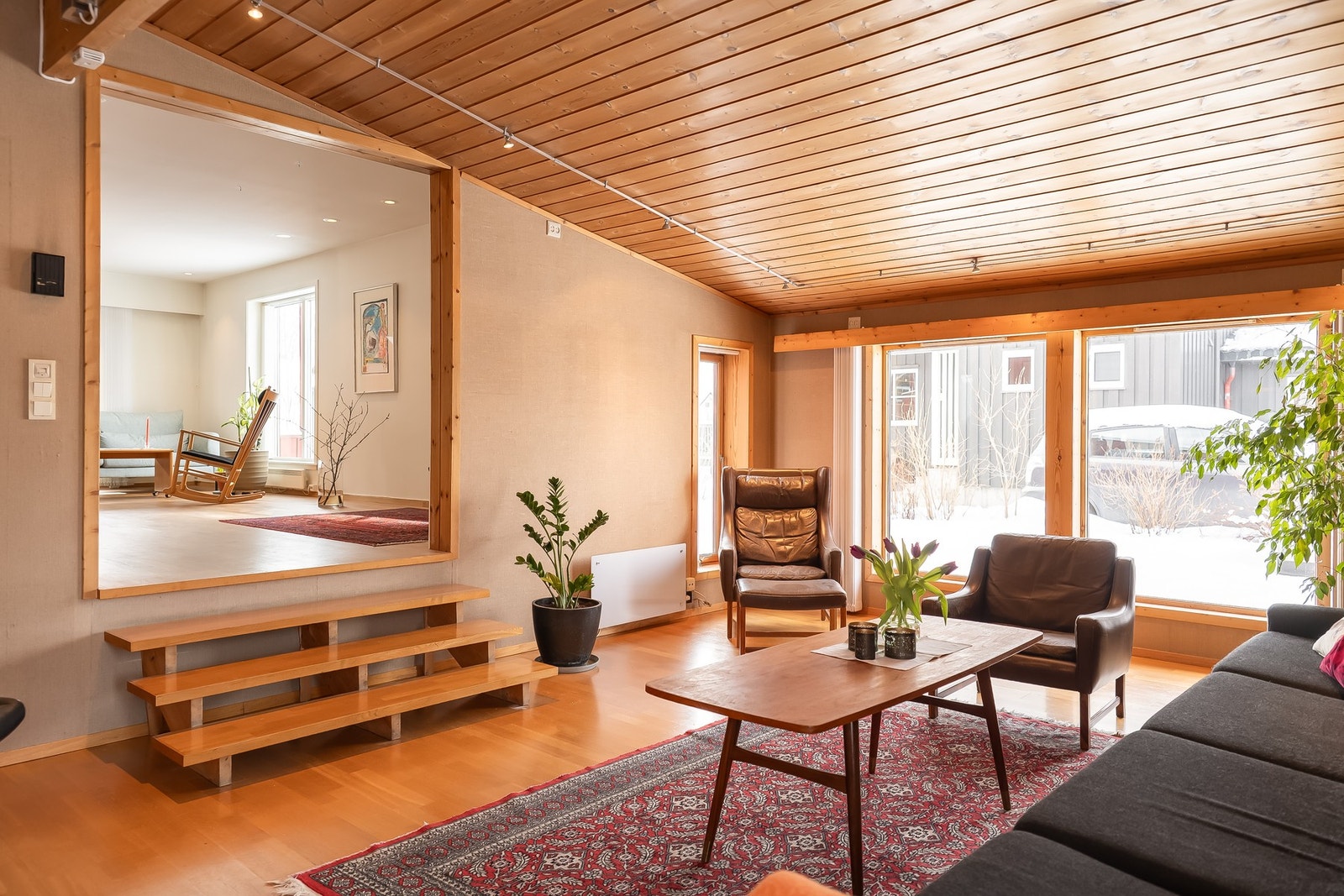 Stue i påbygg ble bygget som en "lounge" med trappetrinn ned og ekstra god takhøyde som setter sitt særpreg på rommet og huset. Galleribilde