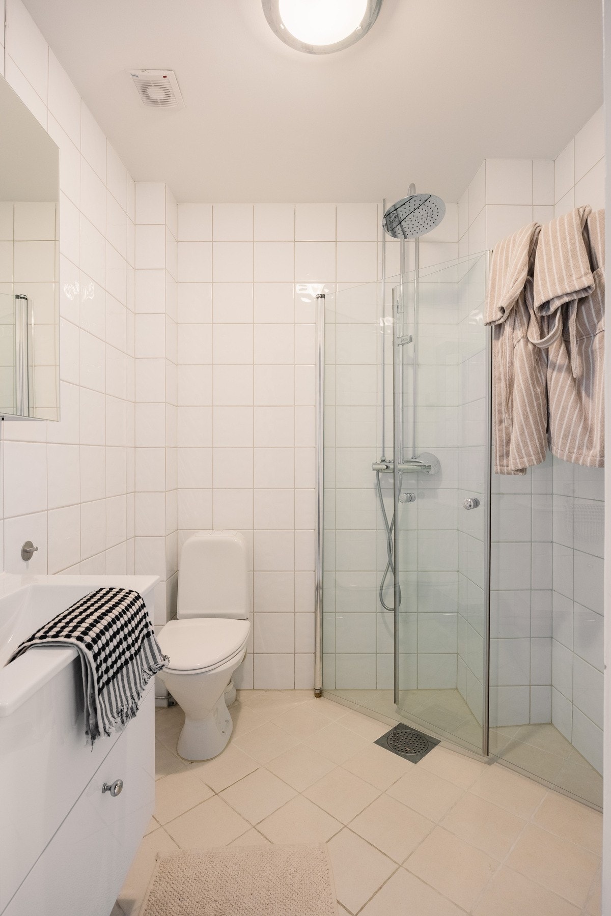 Lyse fliser, varmekabler og dusjnisje med waterfall og hånddusj og opplegg til vask og tørk. Galleribilde