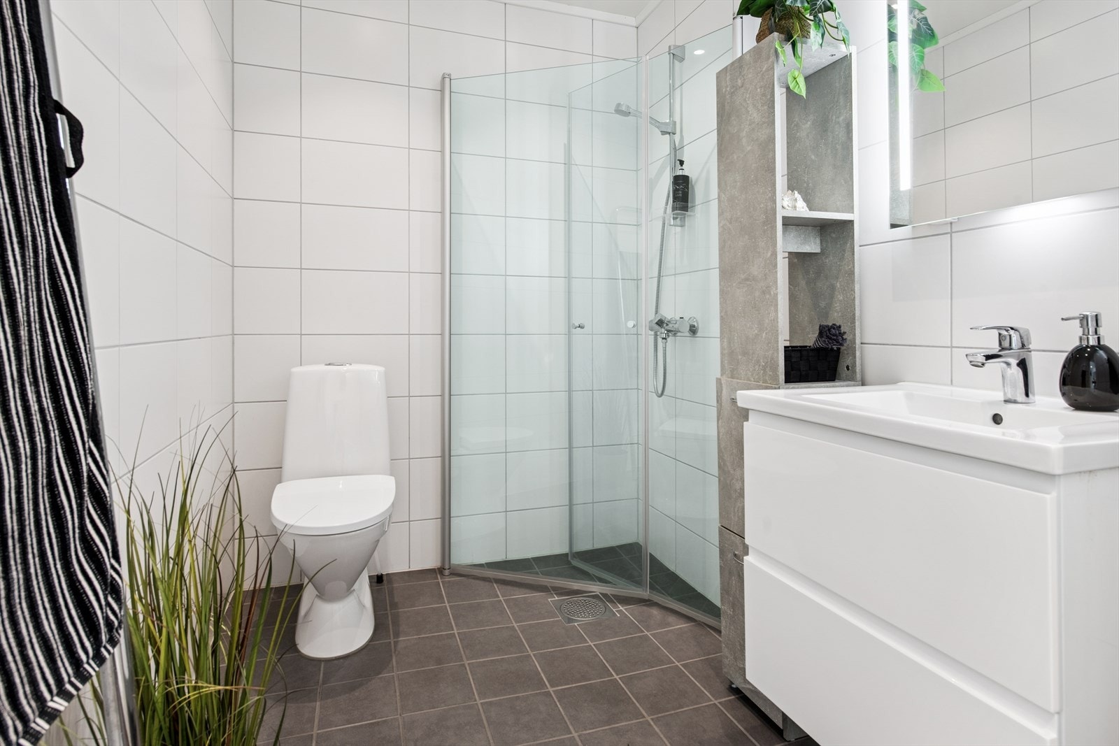 Pent flislagt bad med moderne innredning og dusj med innsvingbare glassdører. Badet er praktisk plassert i hovedetasjen. Galleribilde