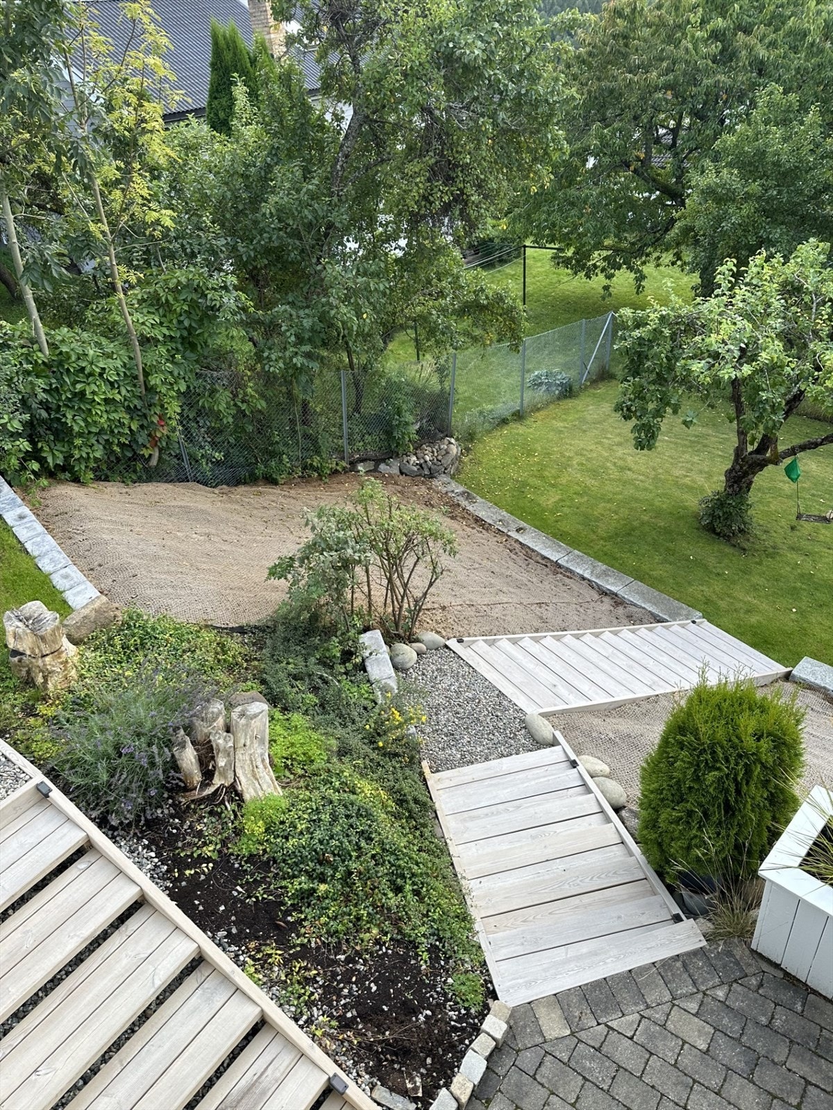 Trappen til hagen er ny i 2025, og skråningene på begge sider er nylig opparbeidet og klargjort for videre beplantning. (Selgers bilde). Galleribilde